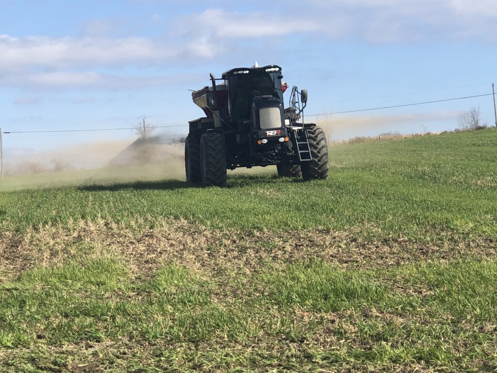 A tractor is driving through the grass on a sunny day.
